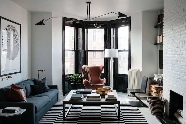La sala tiene paredes blancas y ventanas en negro, creando un constraste elegante en la decoración